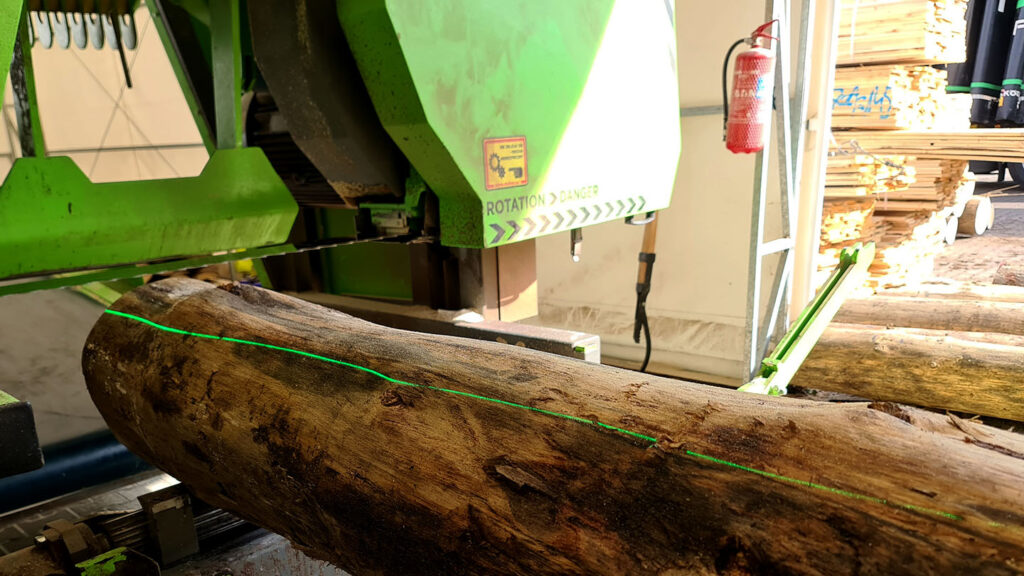 Green line laser LWPRO-520-150-RLINE shining on a log placed on a band sawmill to cut the log into planks